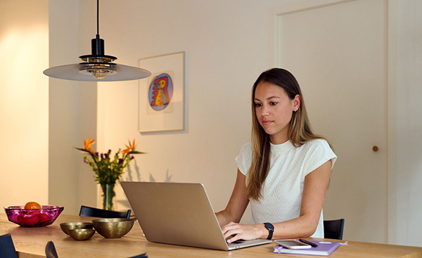 Vrouw zit achter laptop aan tafel